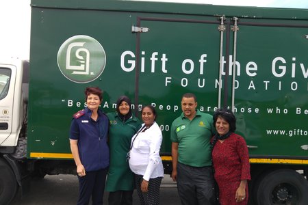 Gift of the Givers se beamptes, saam met Suster Dorothea Jacobs (links) en konst A Naidoo (3de van links) tydens die uitdeel van voedselpakkies